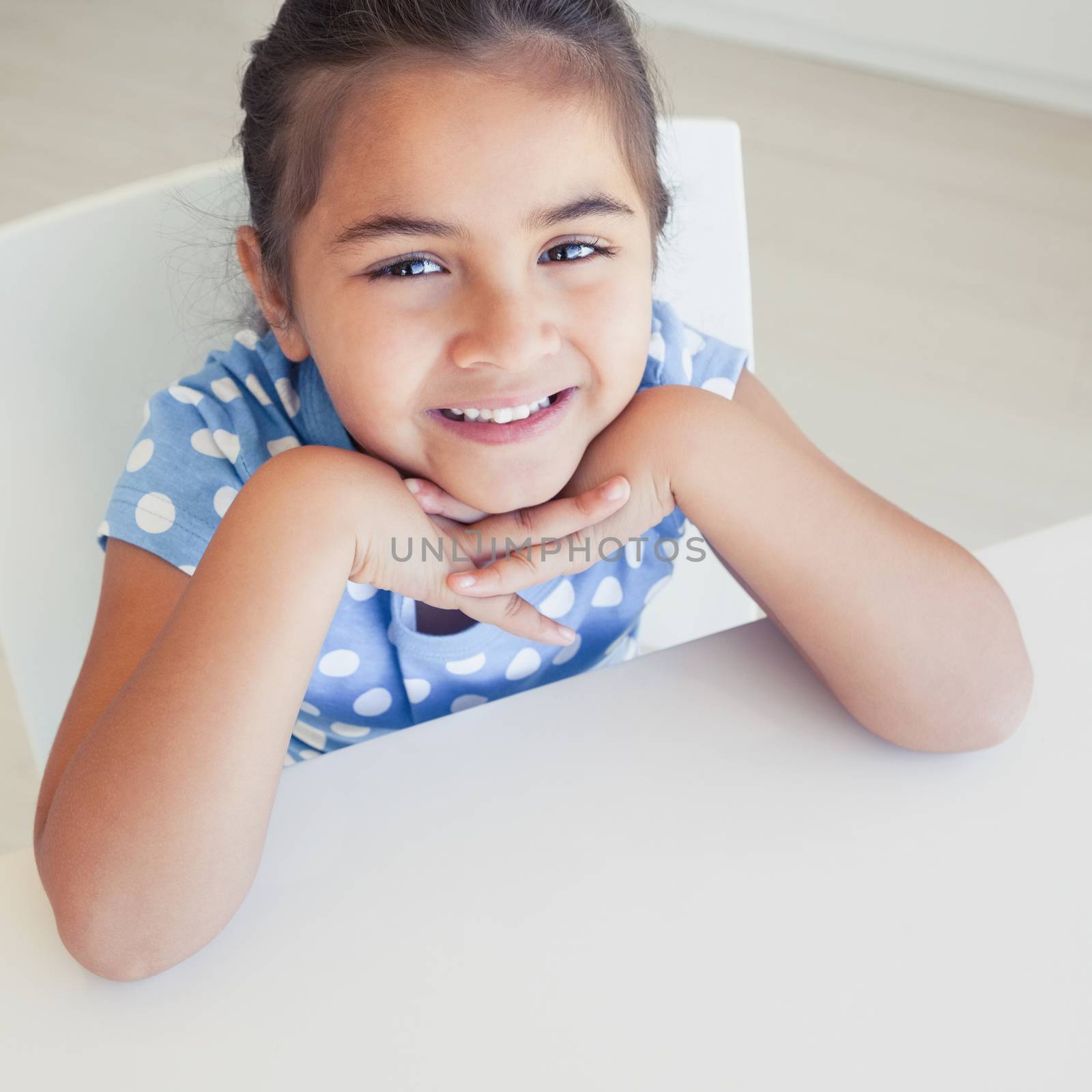 Close-up portrait of a smiling young girl sitting at table
