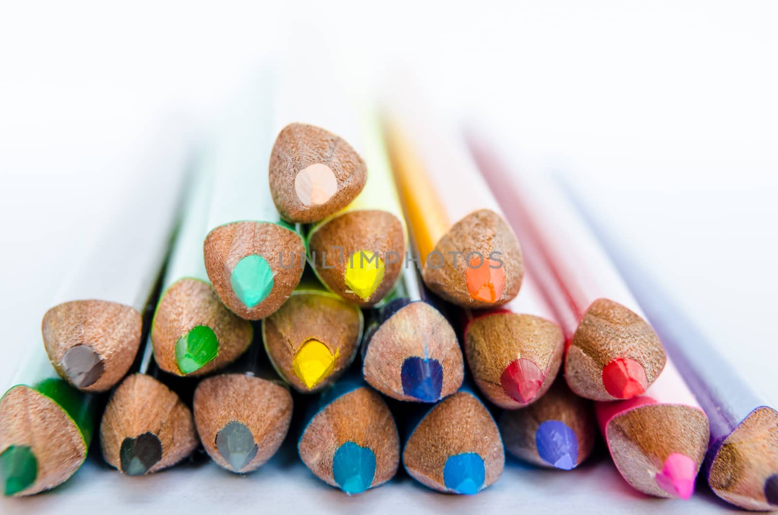Close up detail of colorful pencils in a small stack on white background