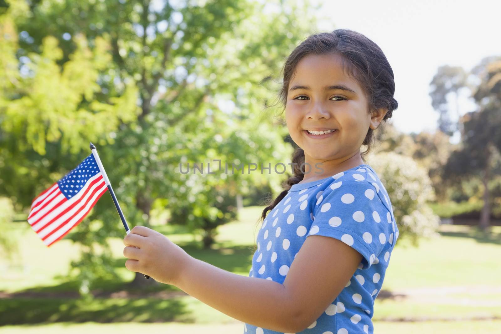 Portrait of a young girl holding the American flag at the park