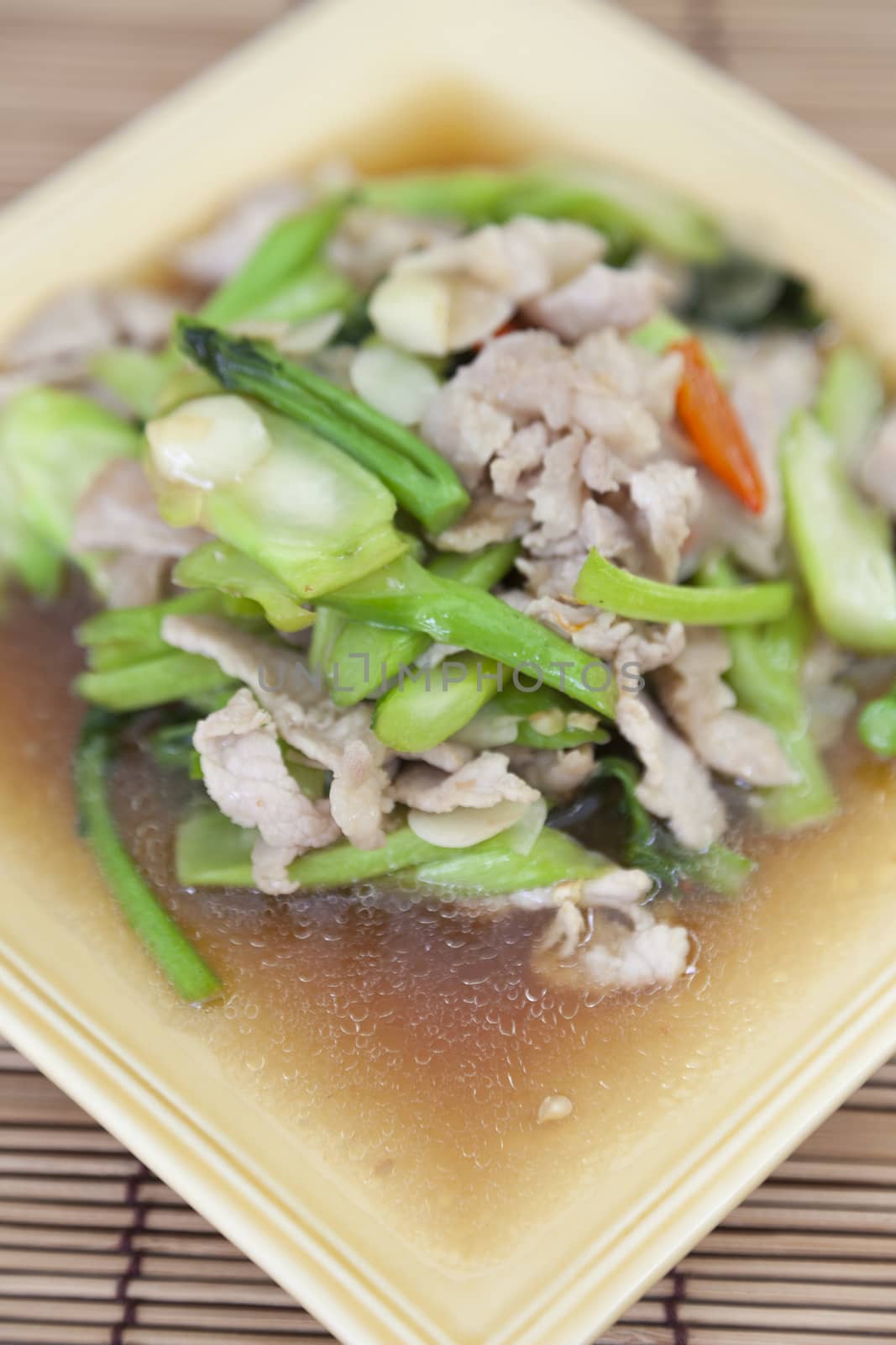 Fried pork with vegetable oil Rectangular plate placed on a wooden plate.