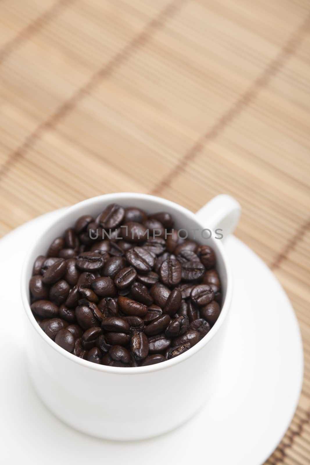 Roasted coffee beans In white coffee cup on wood.