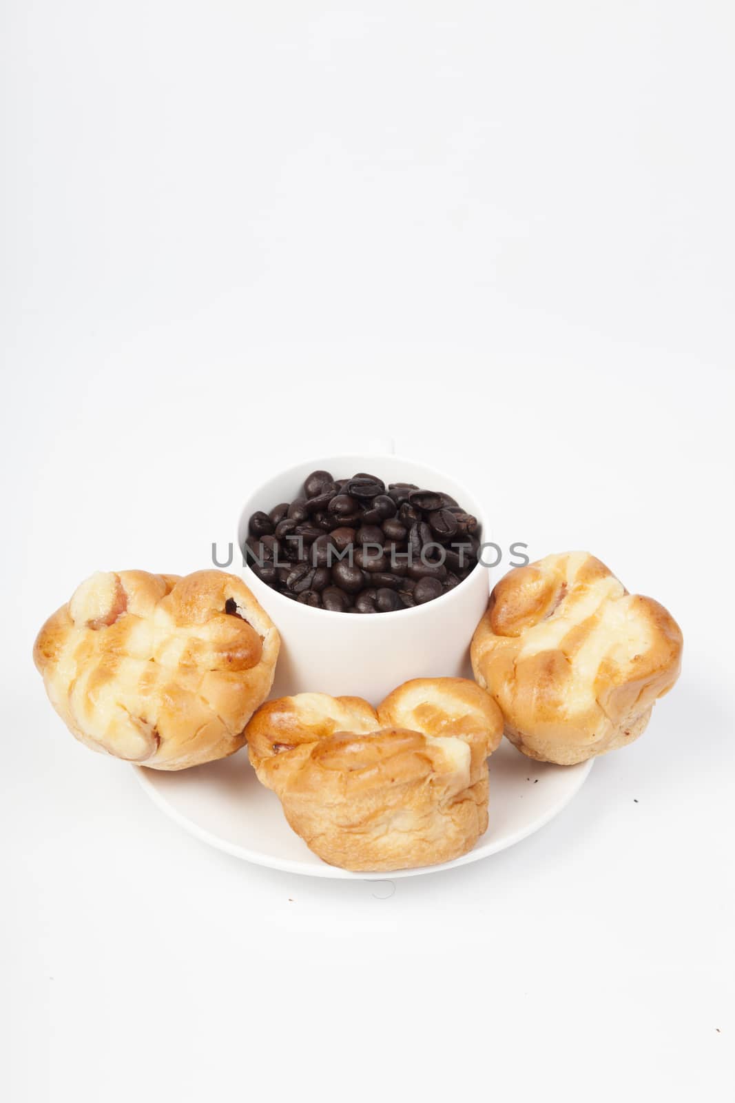 Roasted coffee beans in a glass Bread on plate On a white background