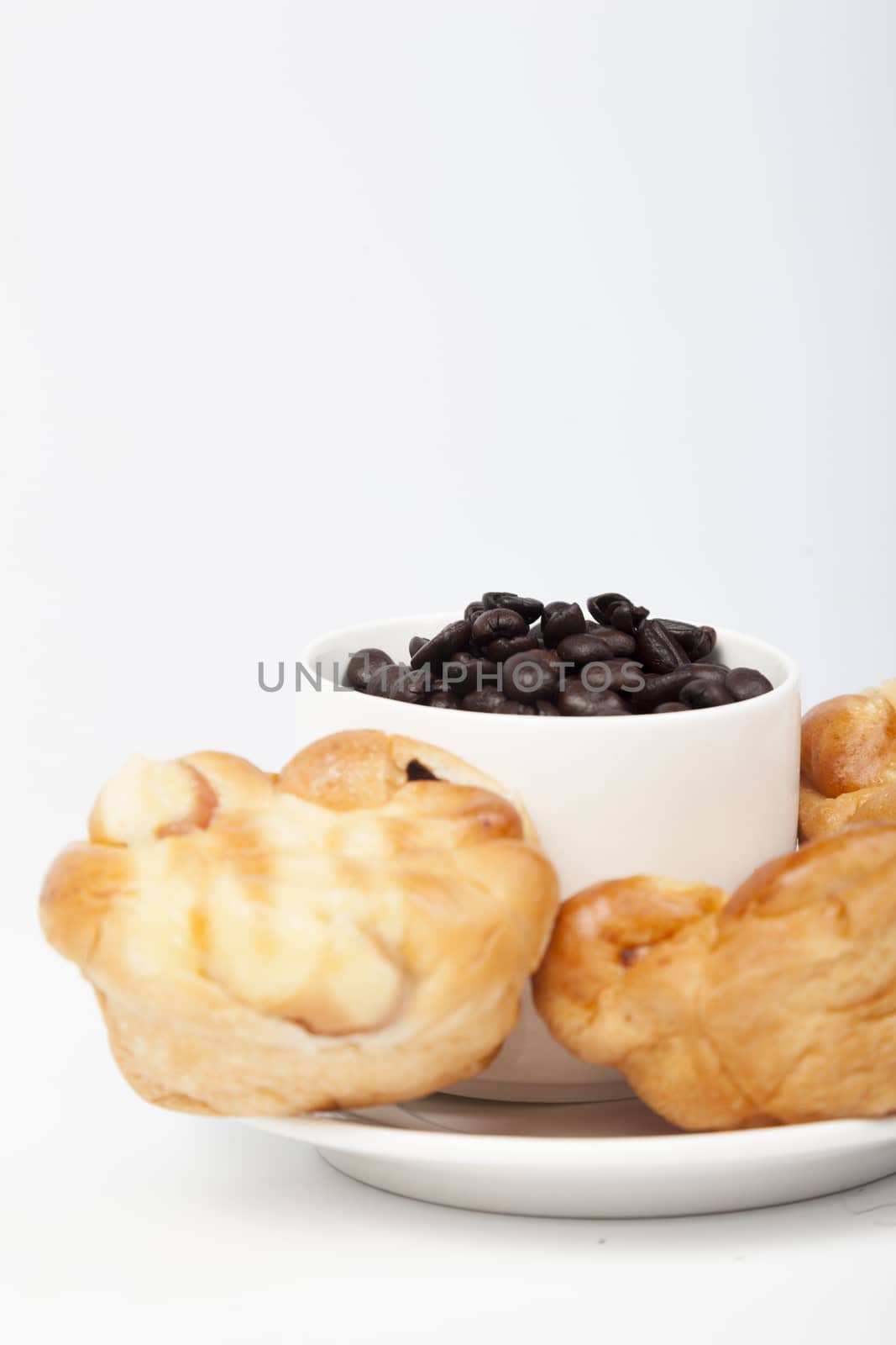 Roasted coffee beans in a glass Bread on plate On a white background