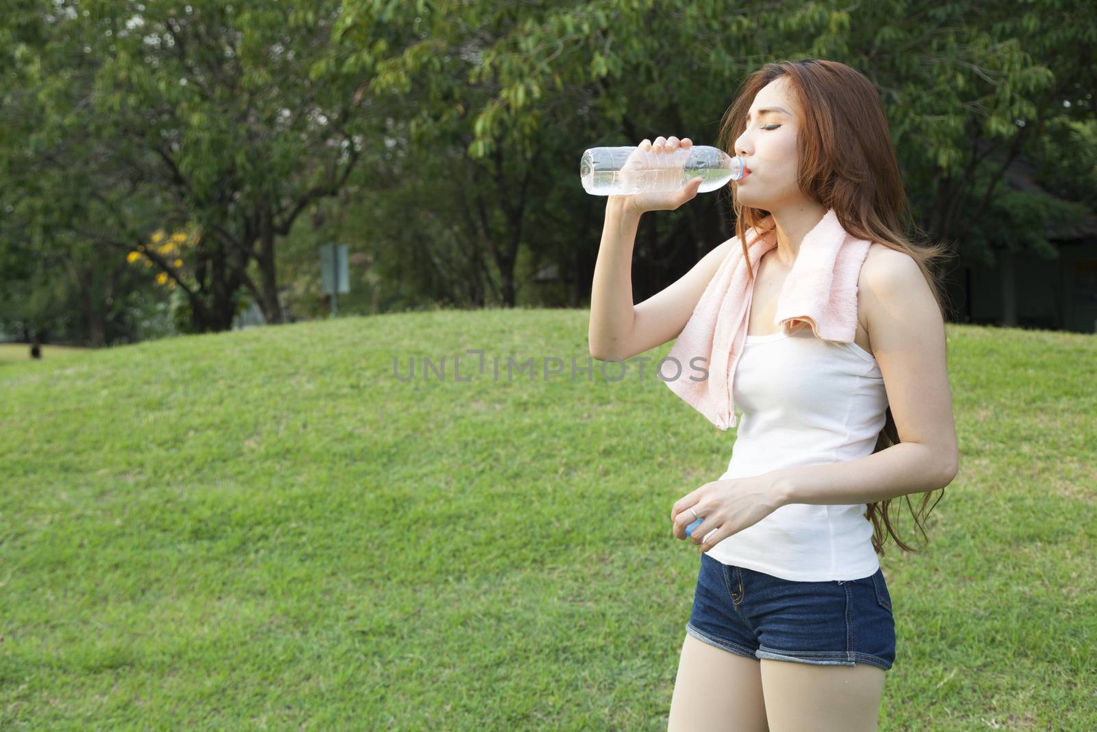 Woman standing water breaks during exercise. Jogging in the park during the evening.
