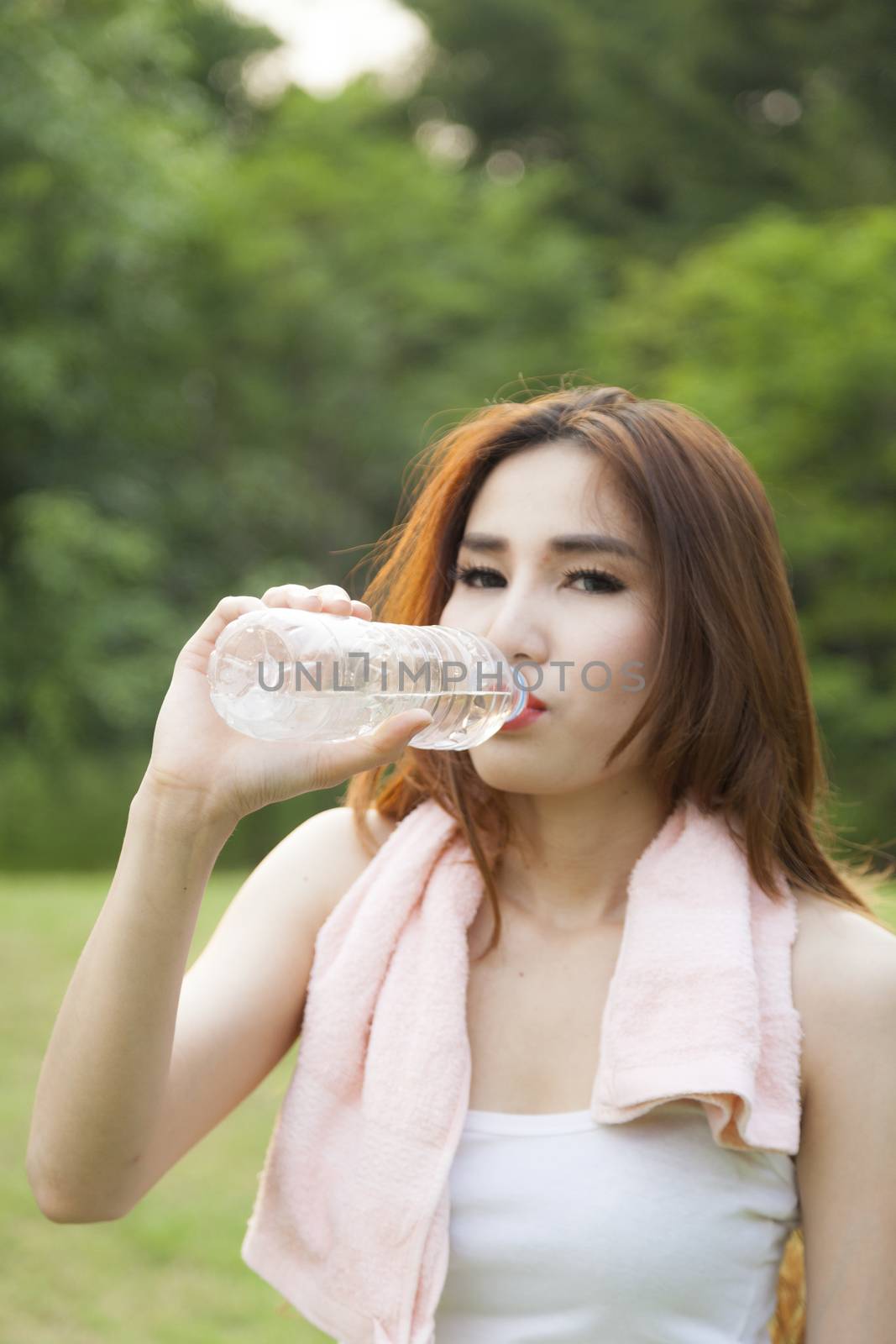 Woman standing water breaks during exercise. Jogging in the park during the evening.