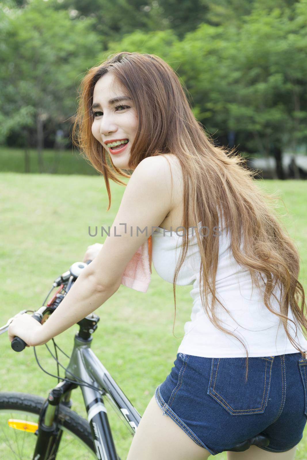Woman riding an exercise bike in the park. On the lawn in the evening.
