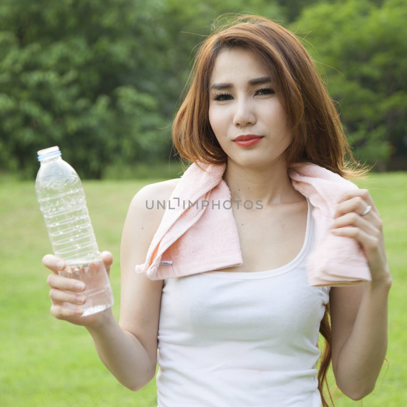 Woman standing water breaks during exercise. Jogging in the park during the evening.