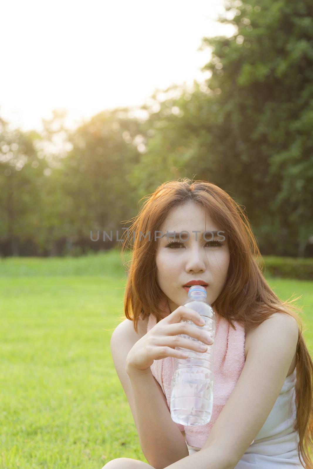 Woman drinking water and sit on grass. by a454
