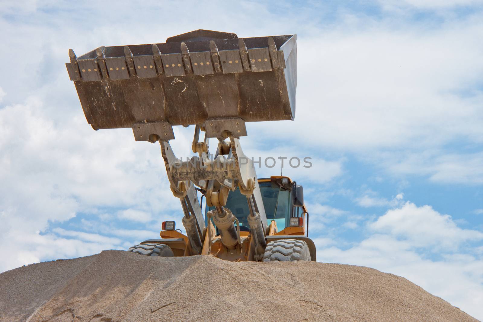 Yellow excavator on a construction site against blue sky