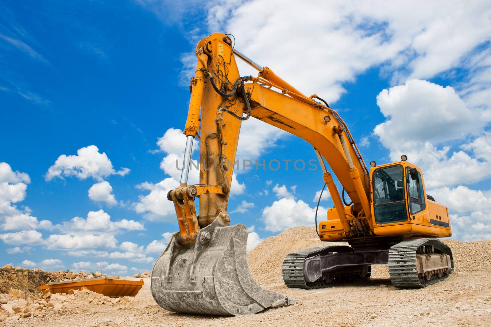 Yellow excavator on a construction site against blue sky by jordanrusev
