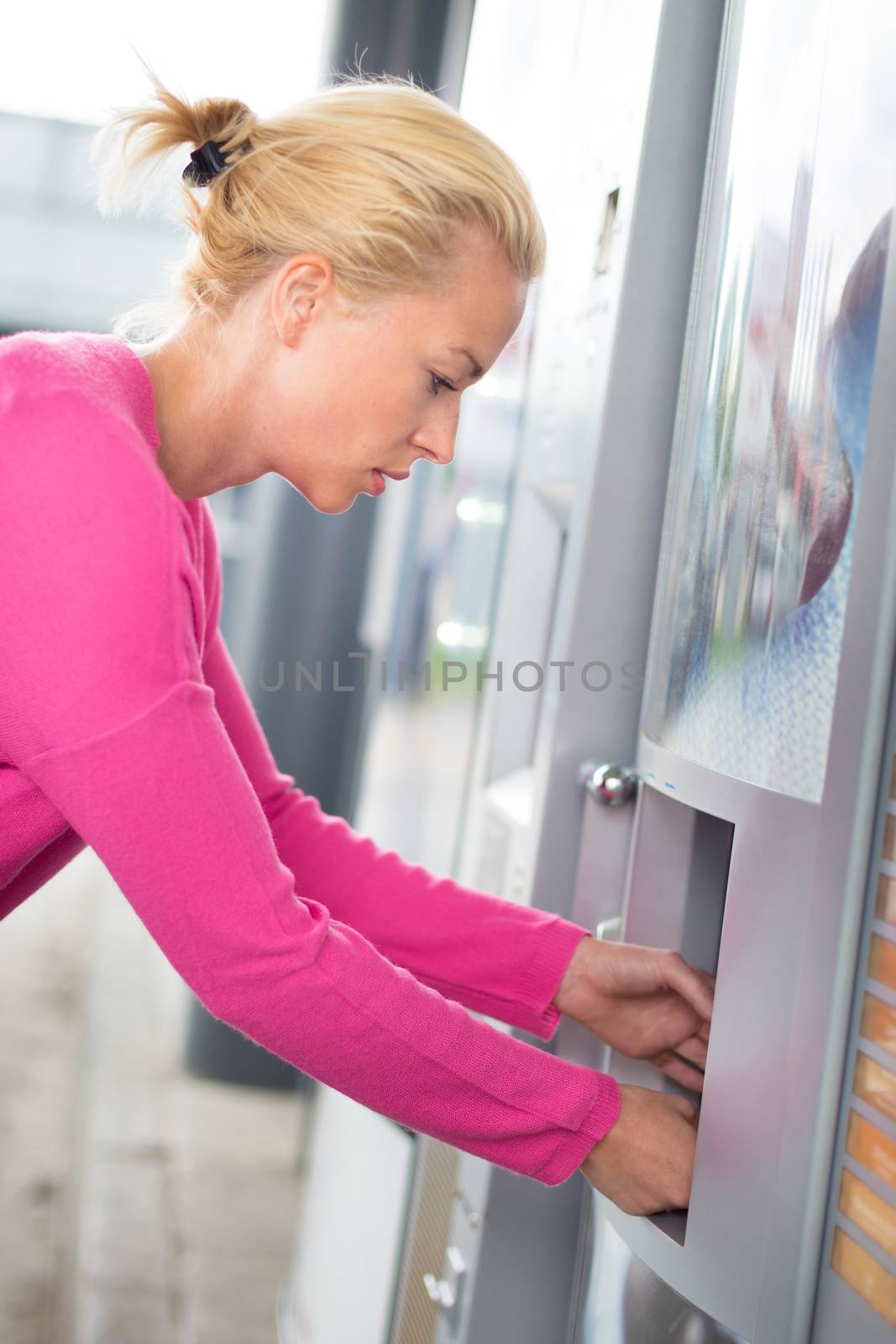 Lady collecting product from vending machine. by kasto