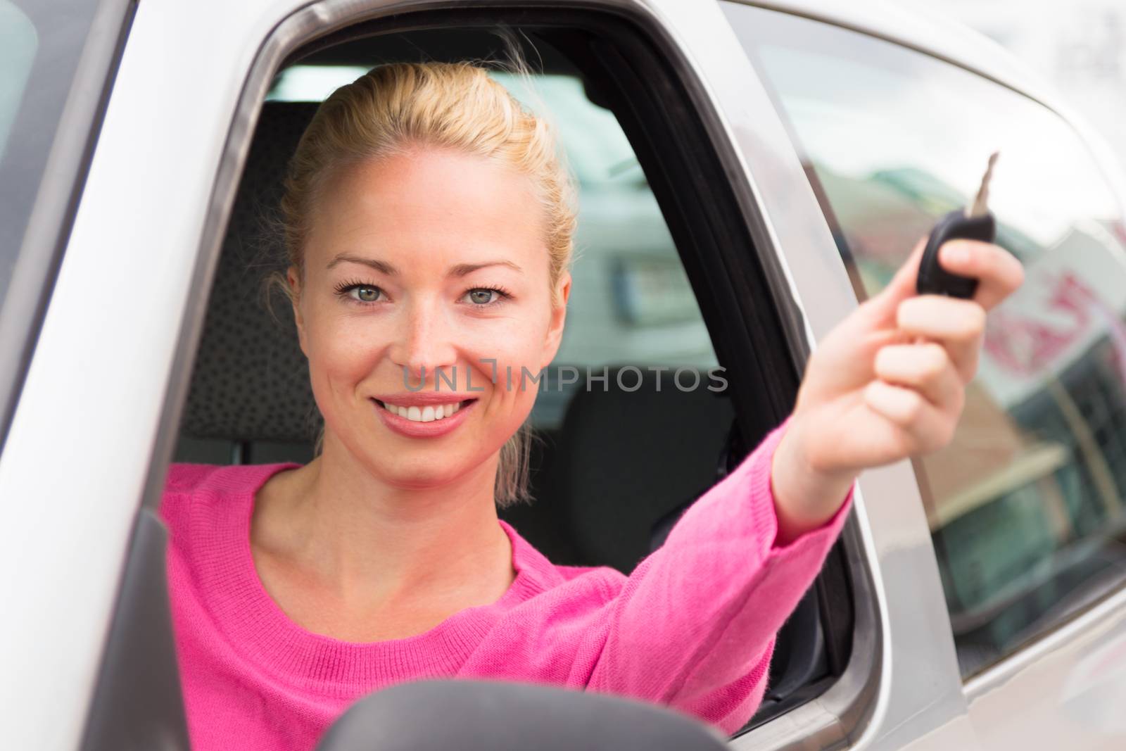 Caucasian lady showing a car key. by kasto