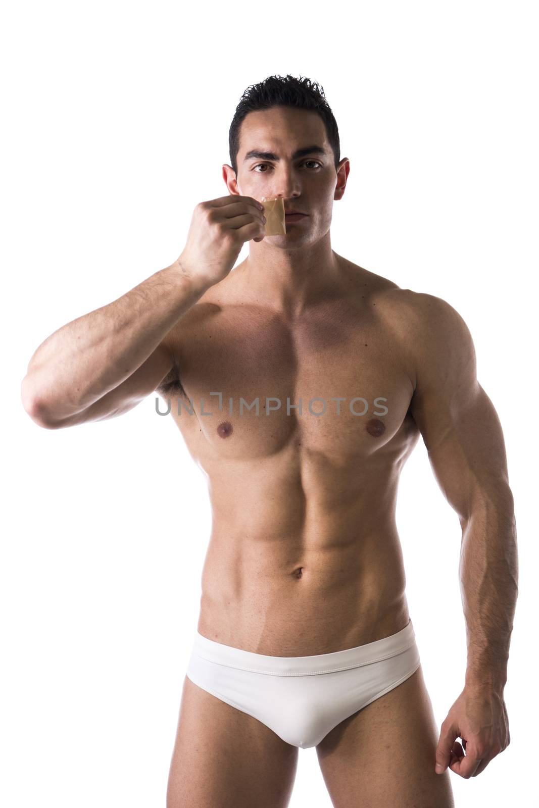 Muscular man in his underwear removing tape from his mouth on white background