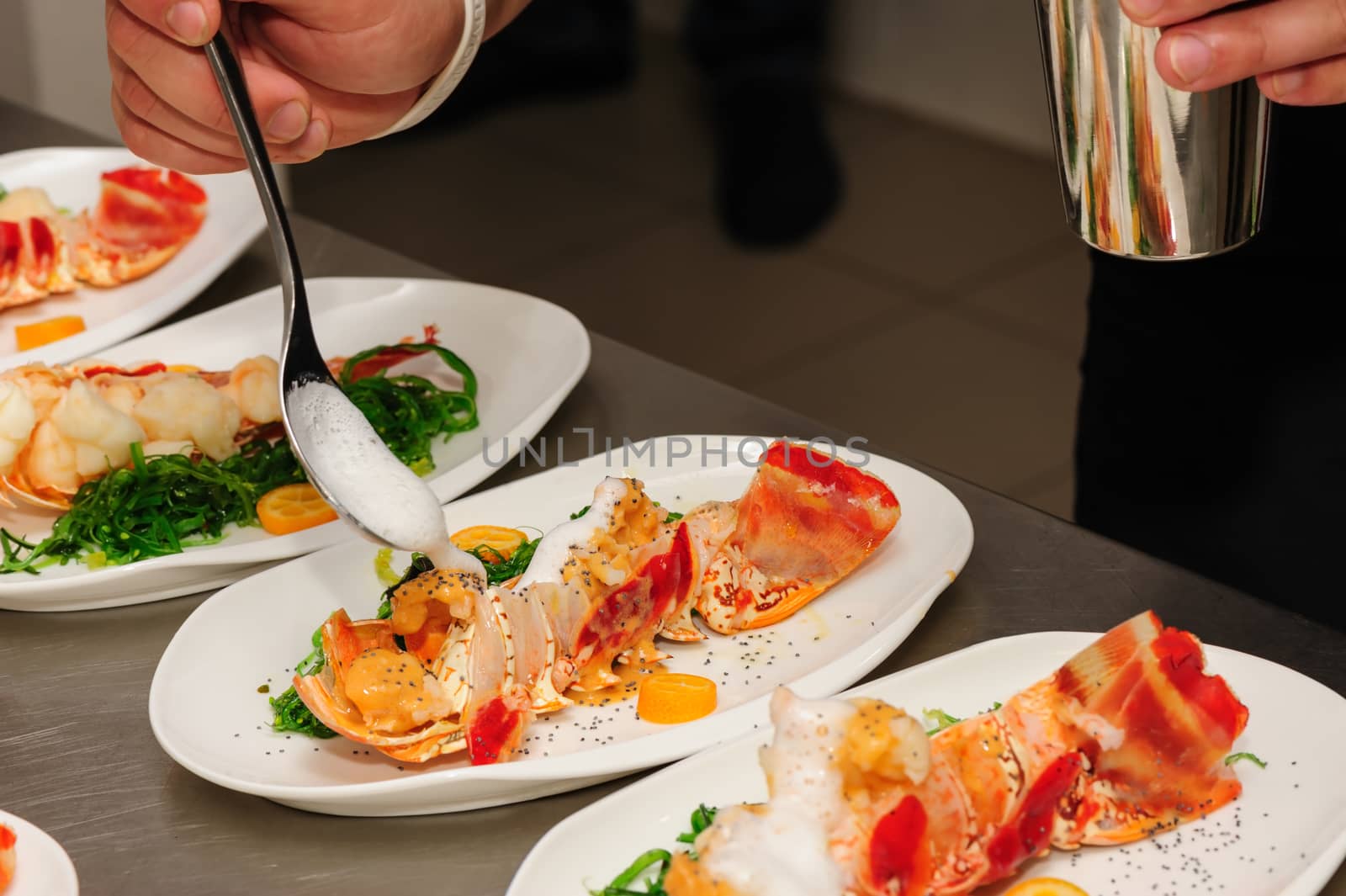 Decorating of prepared lobsters on plates, pouring the foam sauce