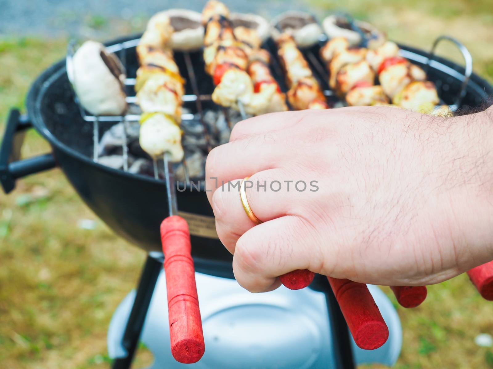 Closeup of a person barbecuing shish with chicken and vegetables by Arvebettum