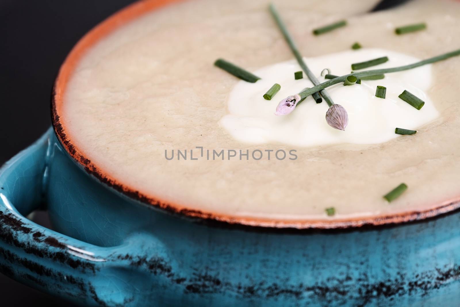 Potato and Leek Soup with sour cream and chives. Extreme shallow depth of field with selective focus on chive flower.