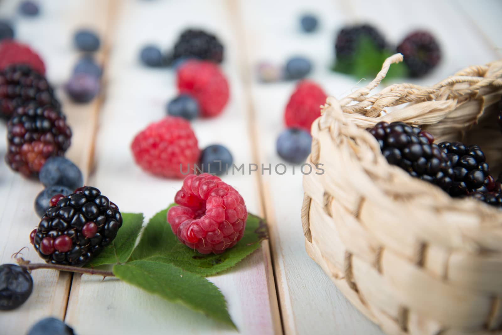 fresh organic berrys fruits in basket on white background retro style wooden table