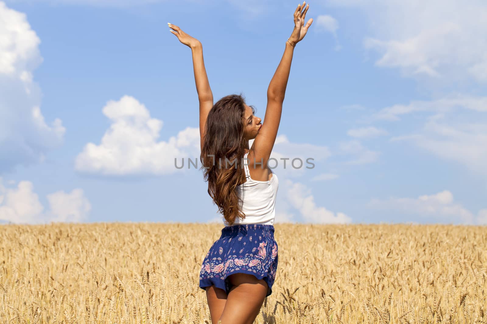 Young woman in a wheat golden field by andersonrise