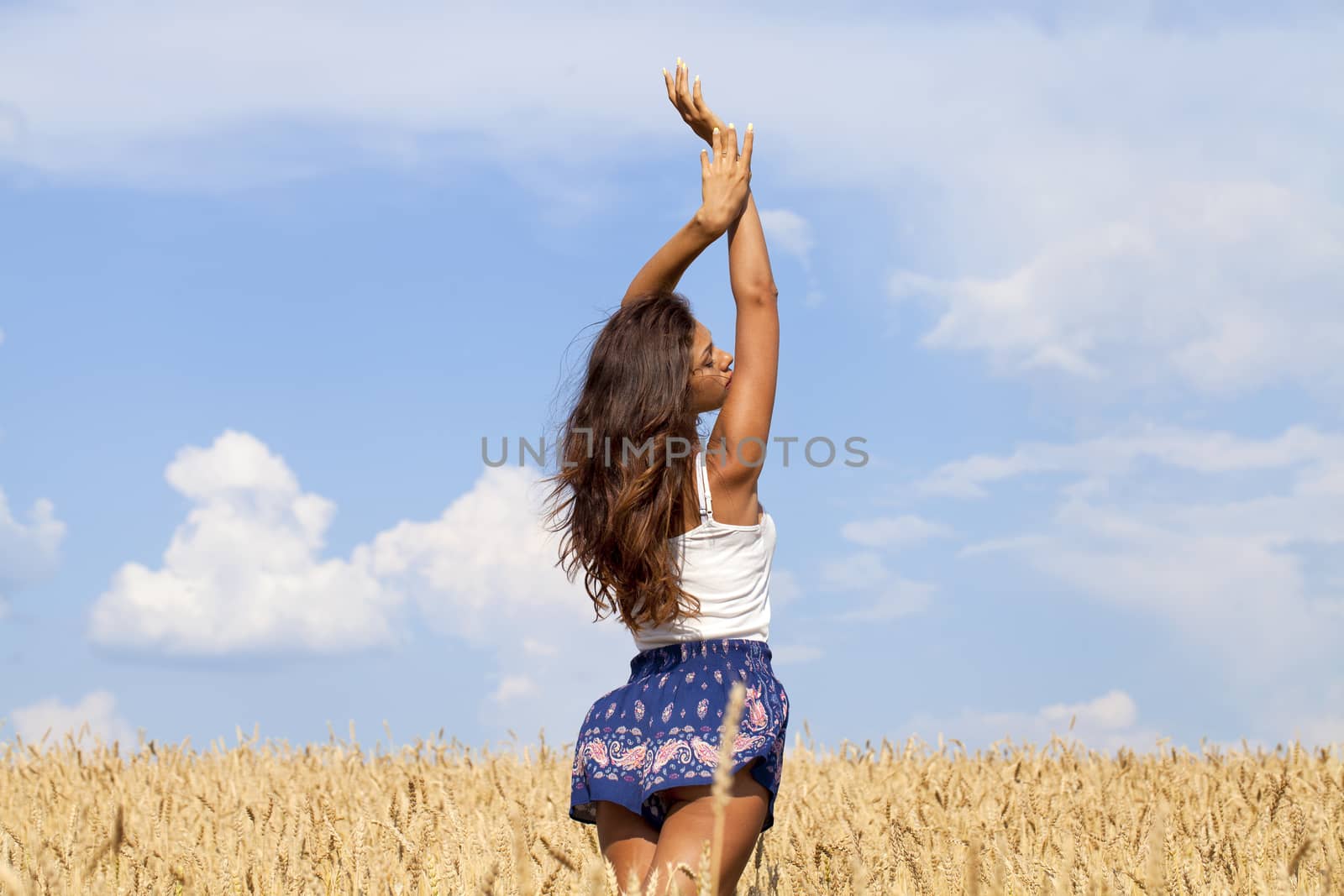 Young woman in a wheat golden field by andersonrise
