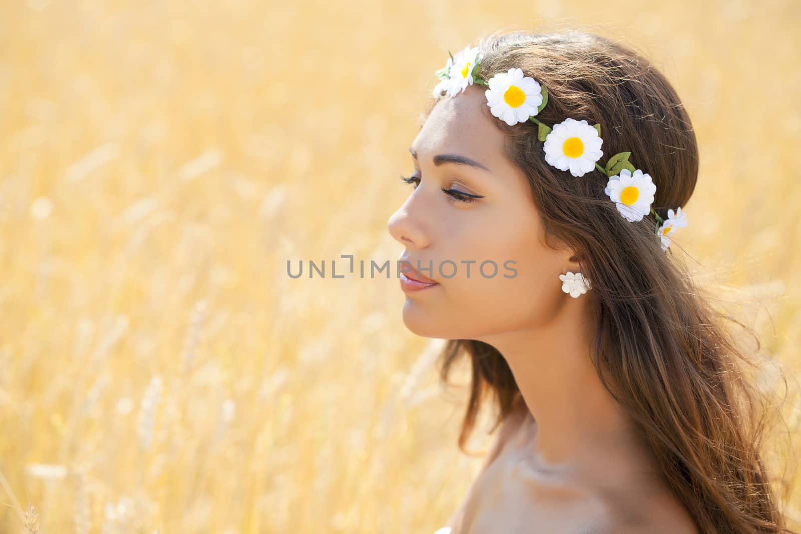 Beautiful young woman in white dress on wheat golden field