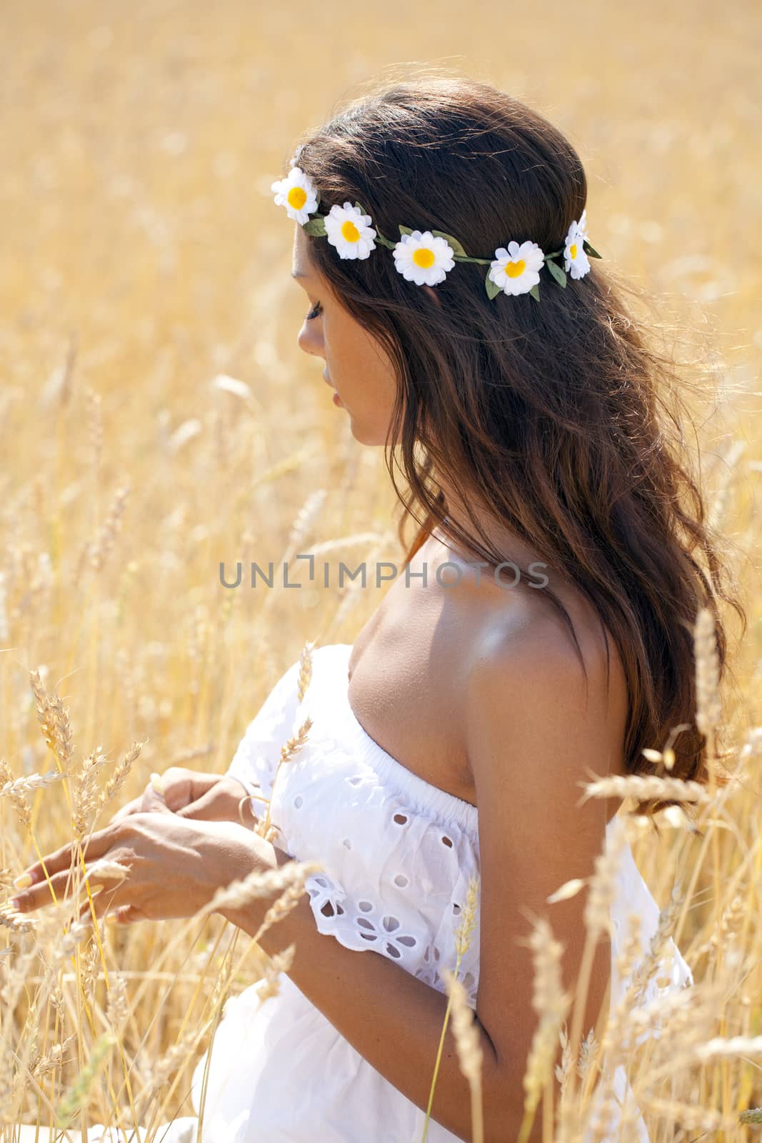 Beautiful young woman in white dress on wheat golden field