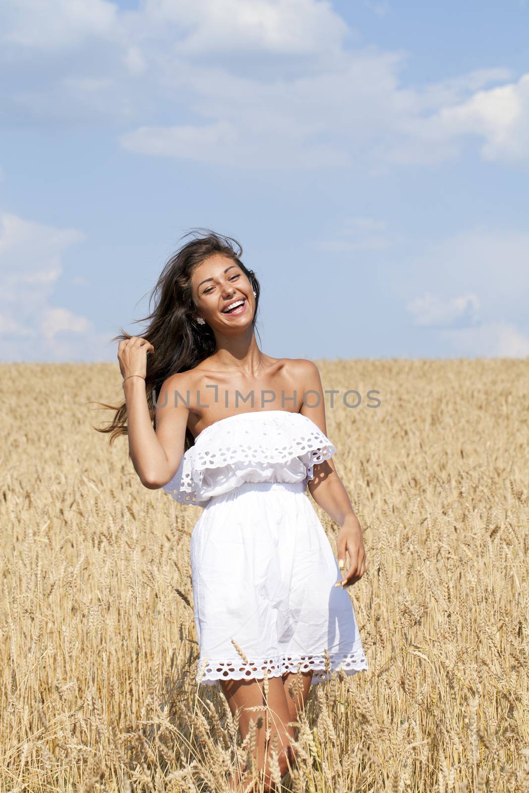 Beautiful young woman in a wheat golden field