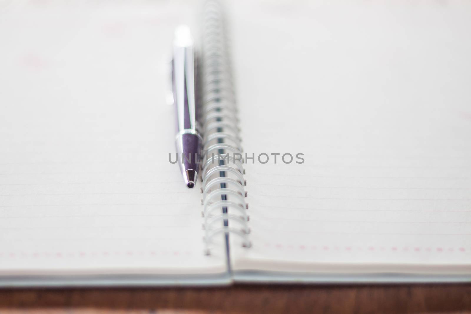 Pen and spiral notebook on wooden table by punsayaporn