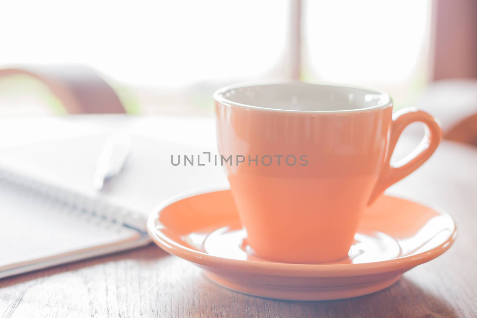 Closeup orange coffee cup in coffee shop by punsayaporn