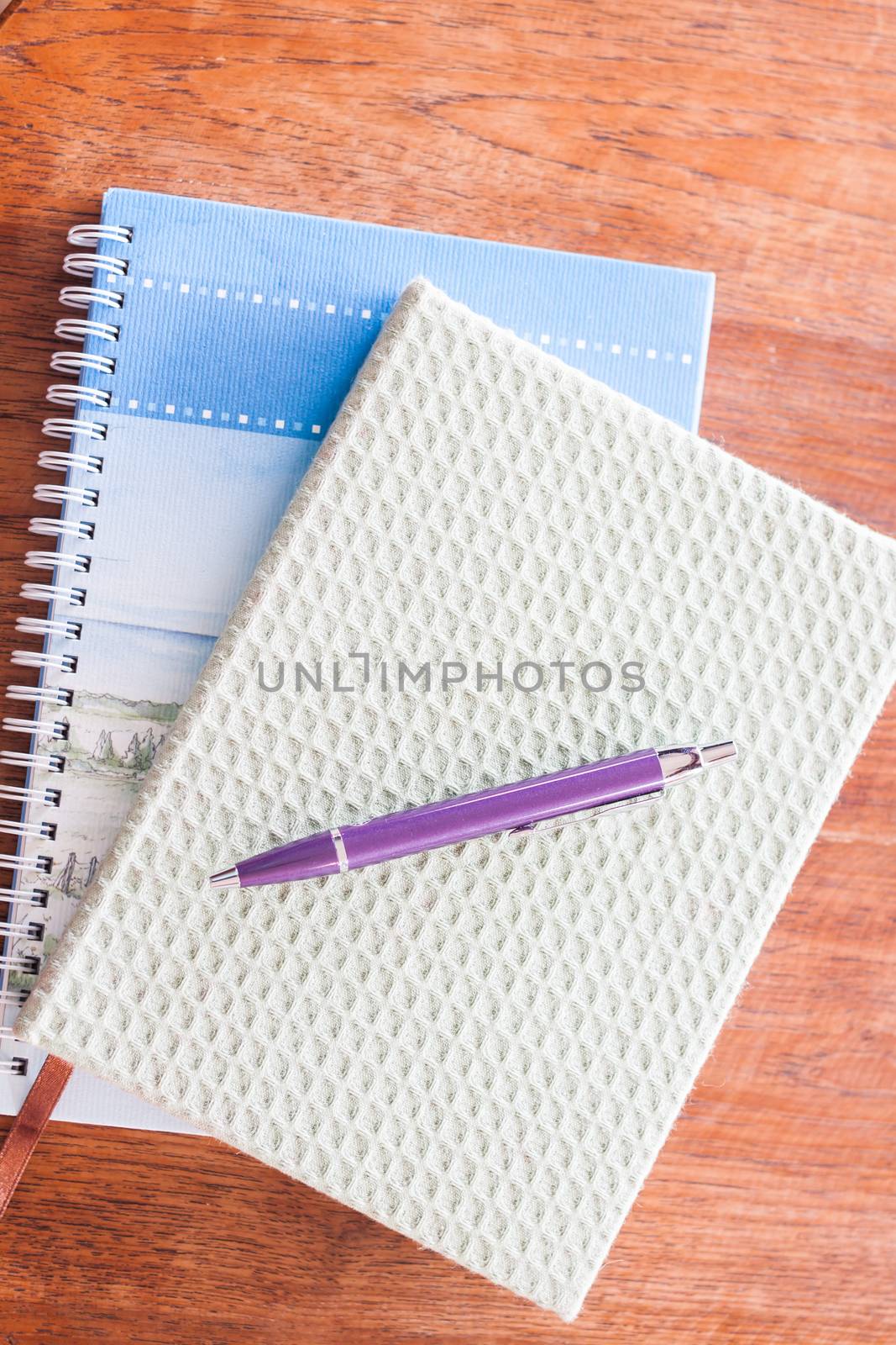 Pen and two of notebooks on wooden table by punsayaporn