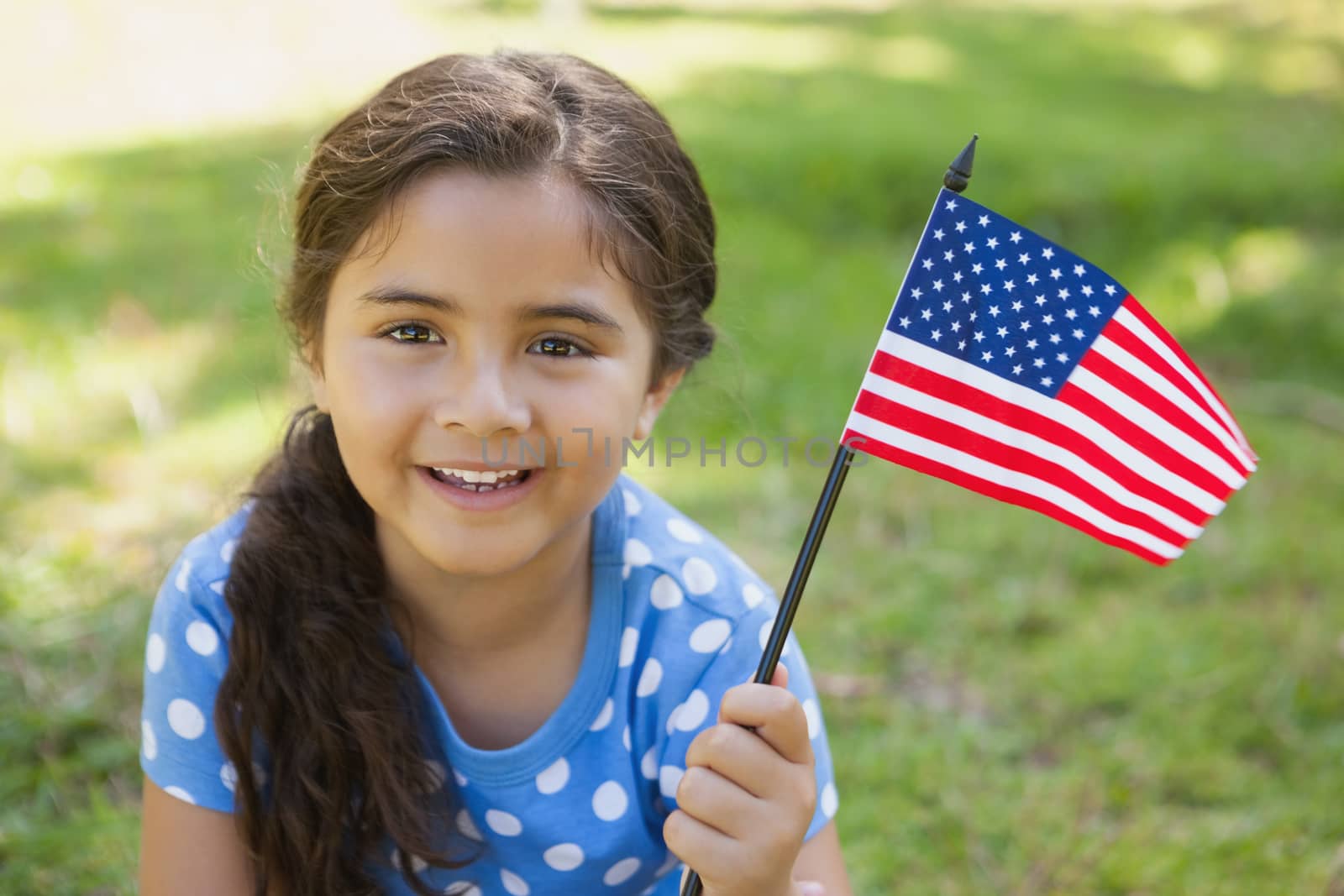 Young girl holding the American flag at park by Wavebreakmedia