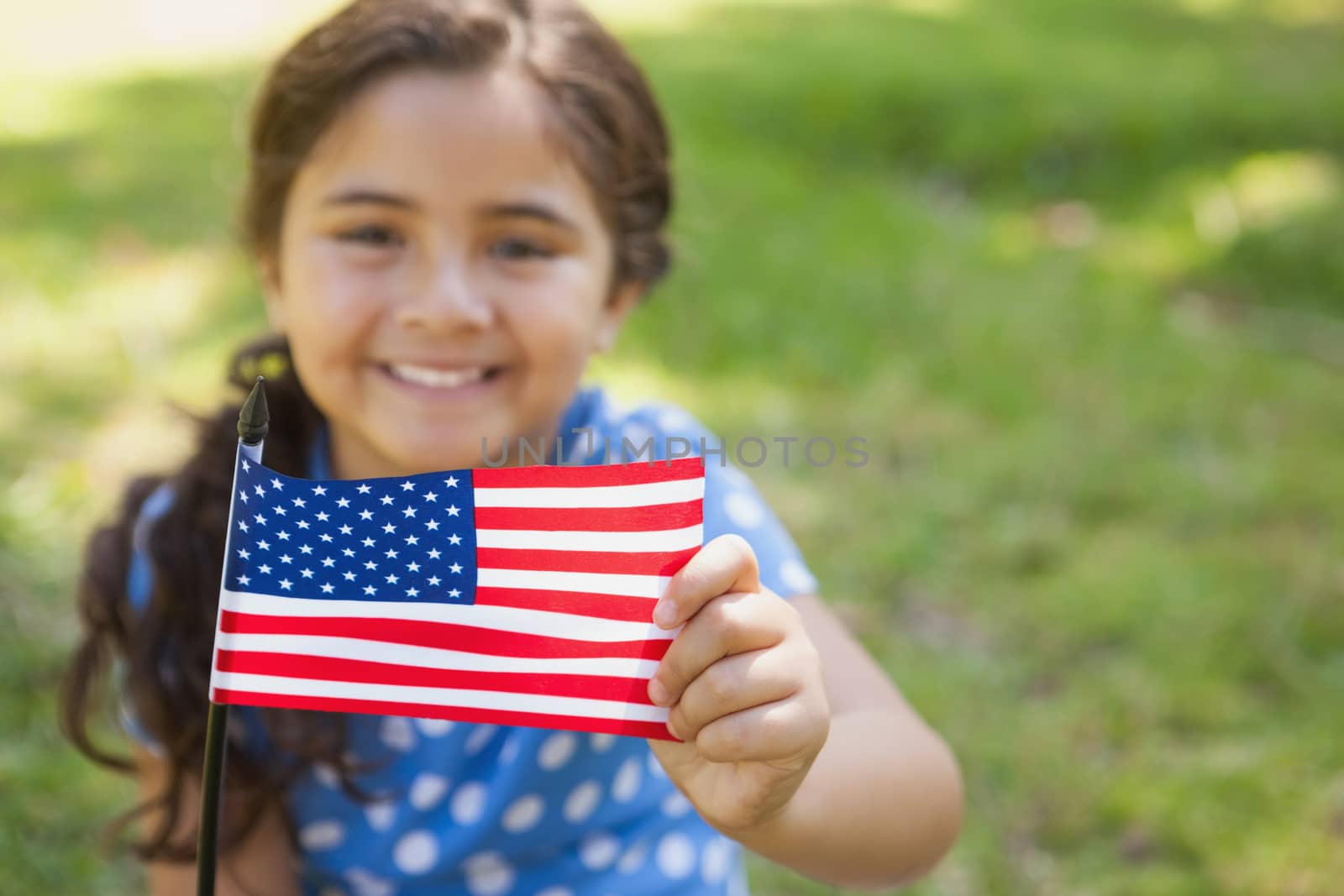 Close-up portrait of a young girl holding the American flag at the park