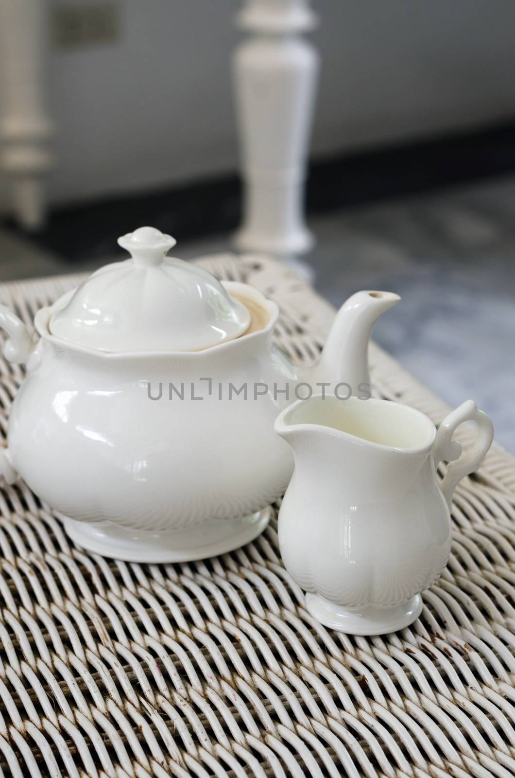 Teapot with little milk jar on weave texture 
