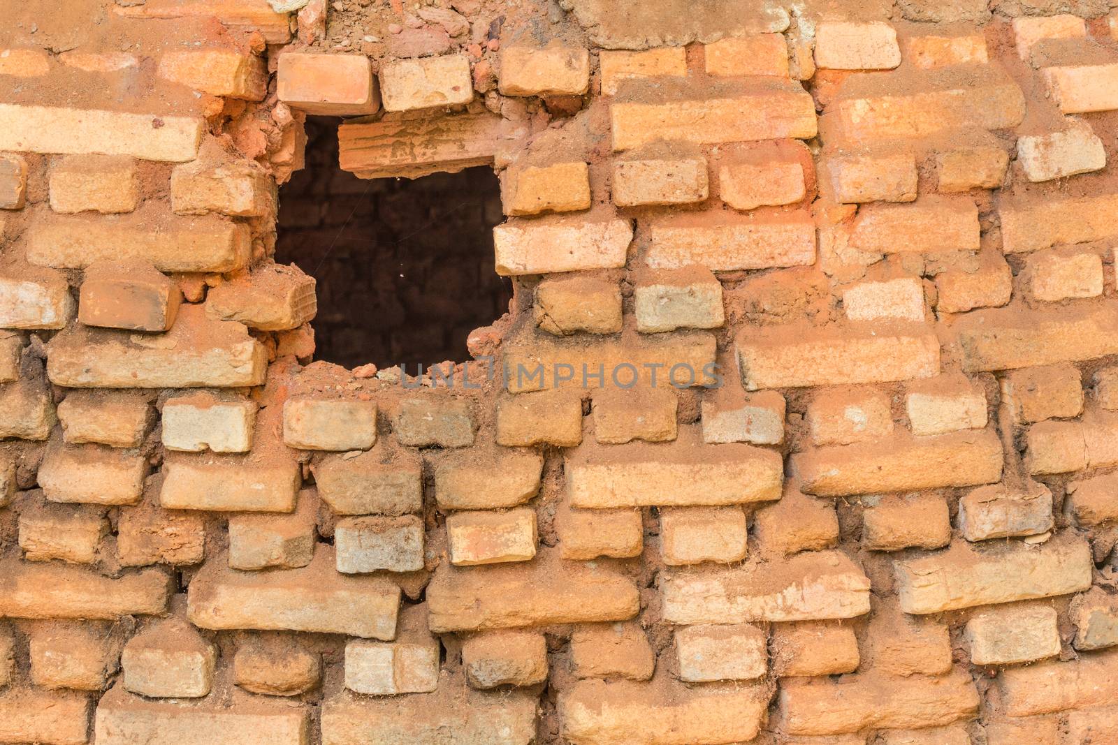 Detail of old weathered red brick wall and hole