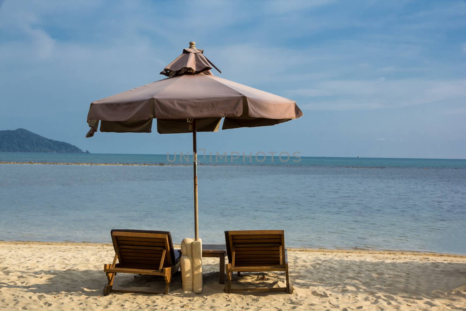 sun lounger and umbrella against blue sea at sun day