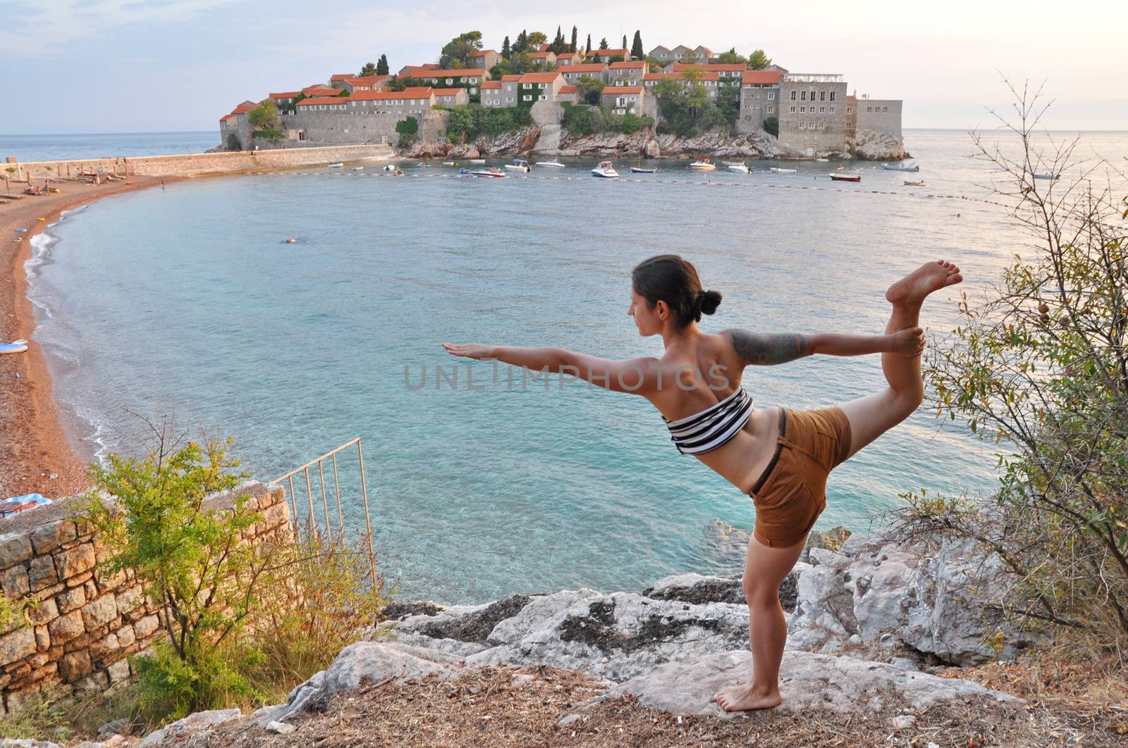 Young woman doing yoga pose at Sveti Stefan, Montenegro