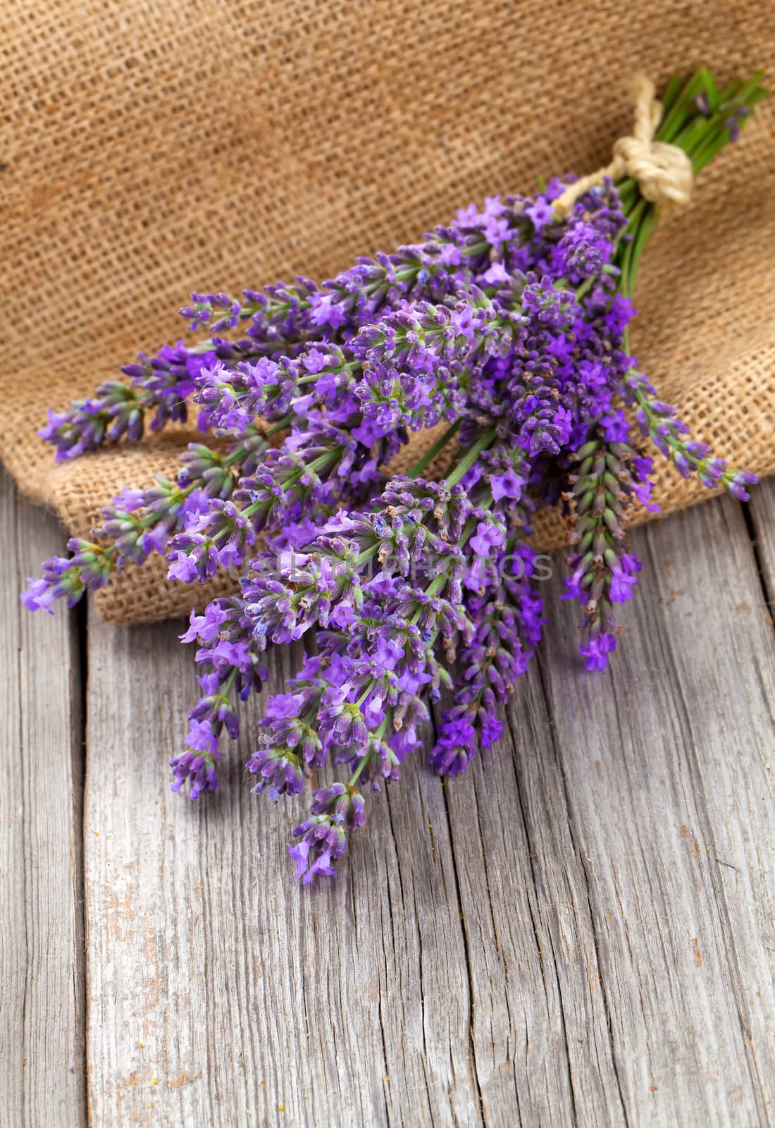 lavender flowers in a basket with burlap on the wooden background