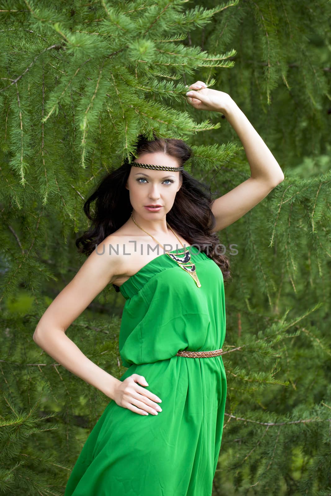 Beautiful young woman in green dress, against green of summer park