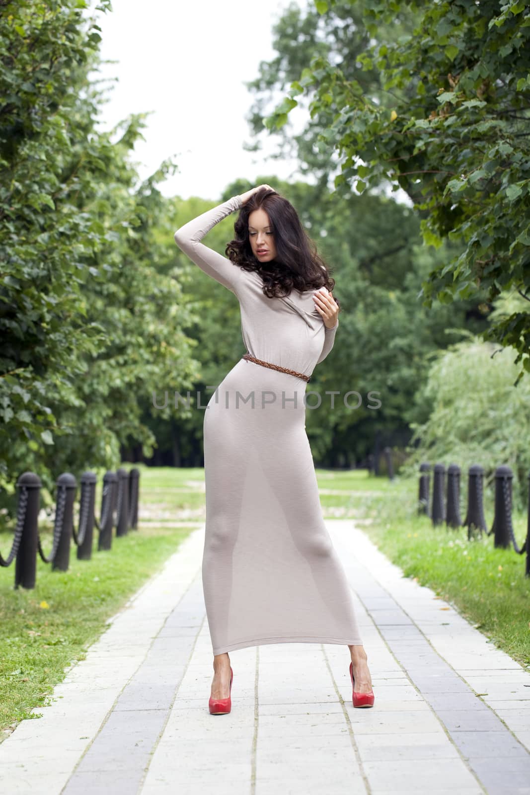 Full growth, beautiful young woman in sexy long gray dress, walking in summer park