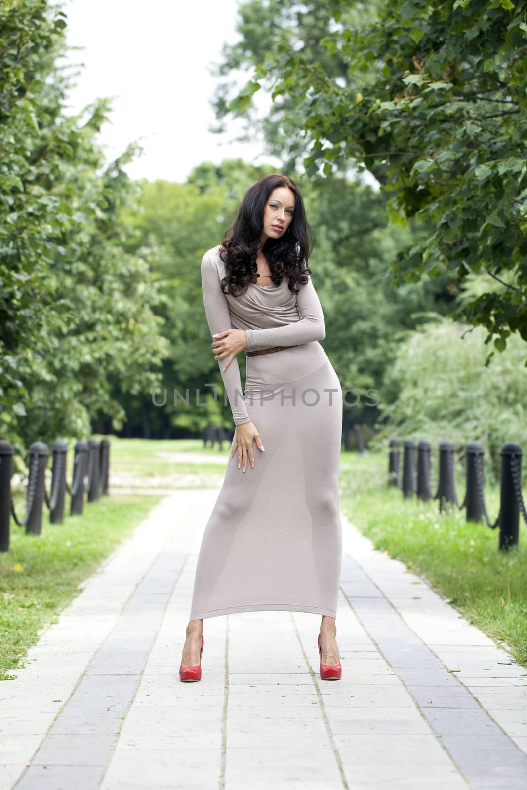 Full growth, beautiful young woman in sexy long gray dress, walking in summer park