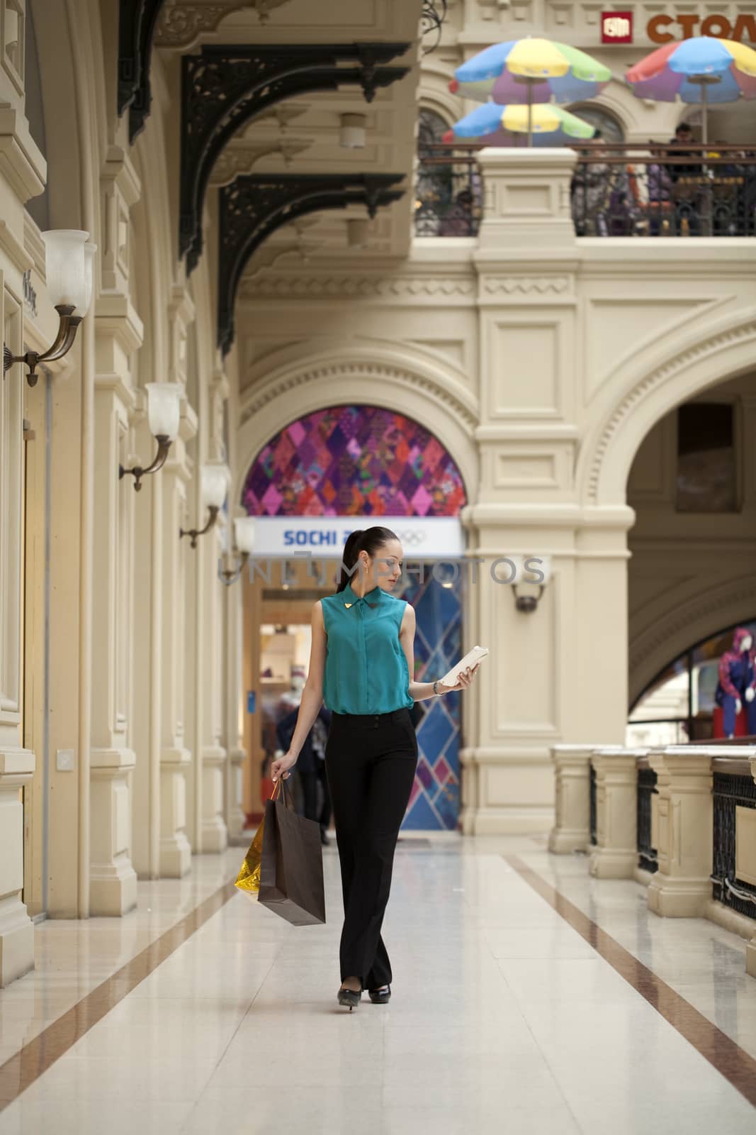 Happy young woman walking in the shop by andersonrise