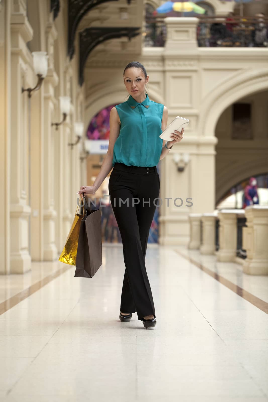 Happy young woman walking in the shop by andersonrise