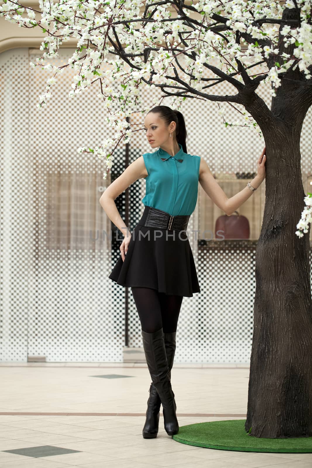 Beautiful young woman standing in full length in the spring tree in the store