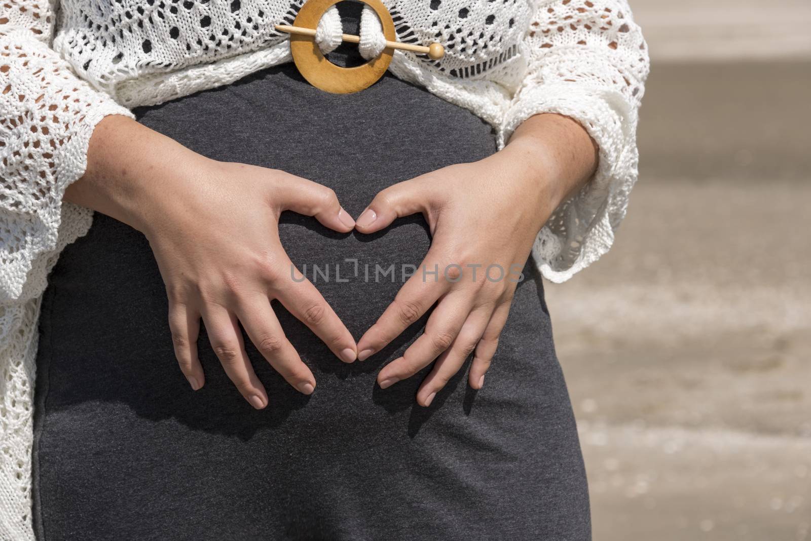 pregnant woman holding her hands on her belly in heart shape