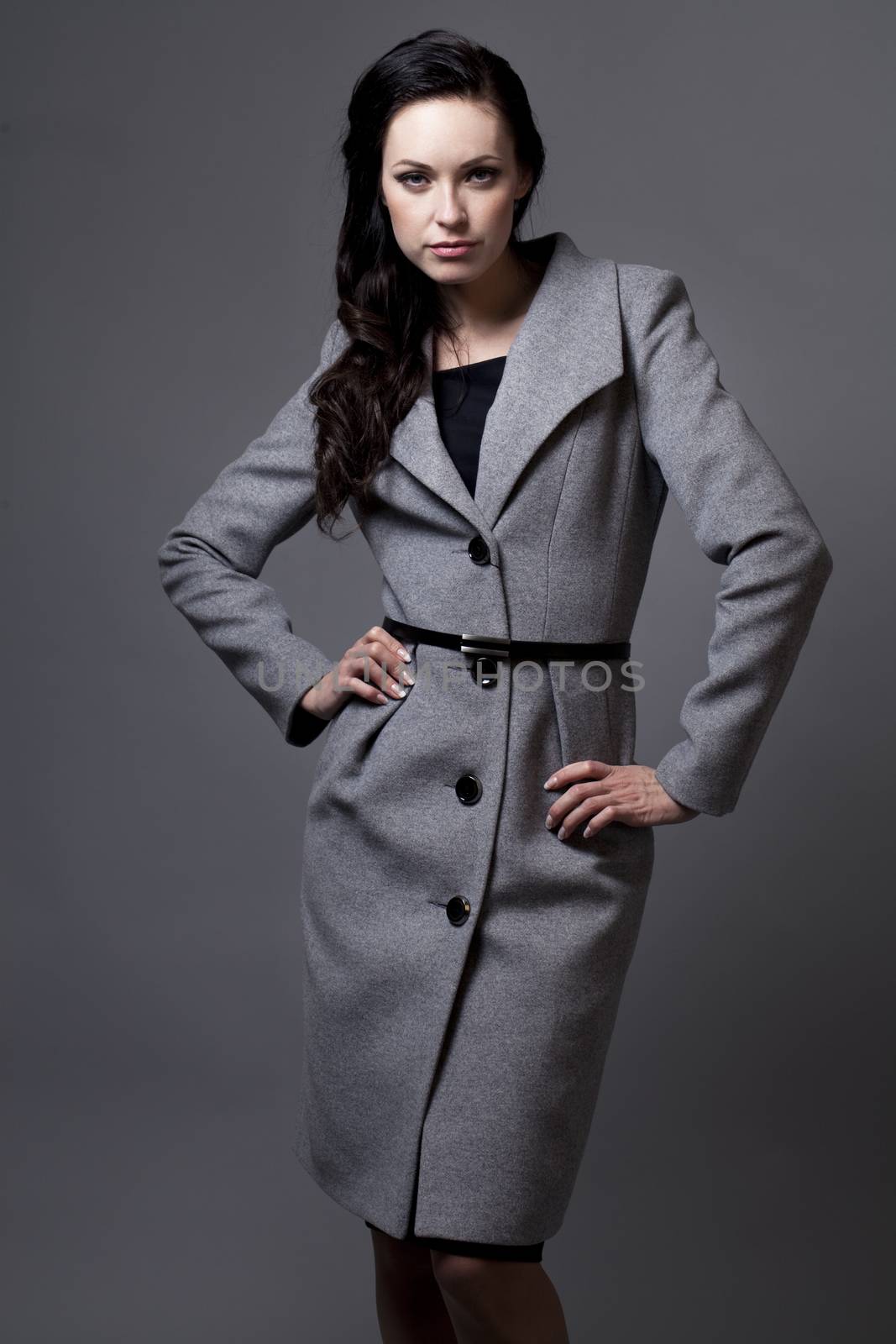 Beautiful young woman in autumn coat against gray background