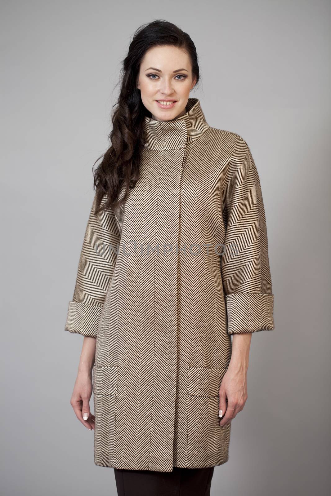 Beautiful young woman in autumn coat against gray background