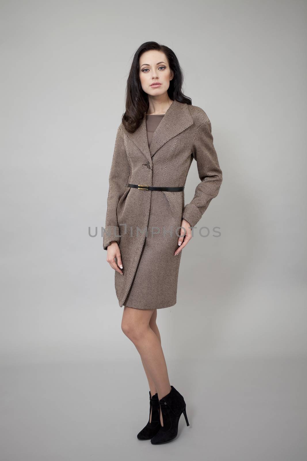 Beautiful young woman in autumn coat against gray background