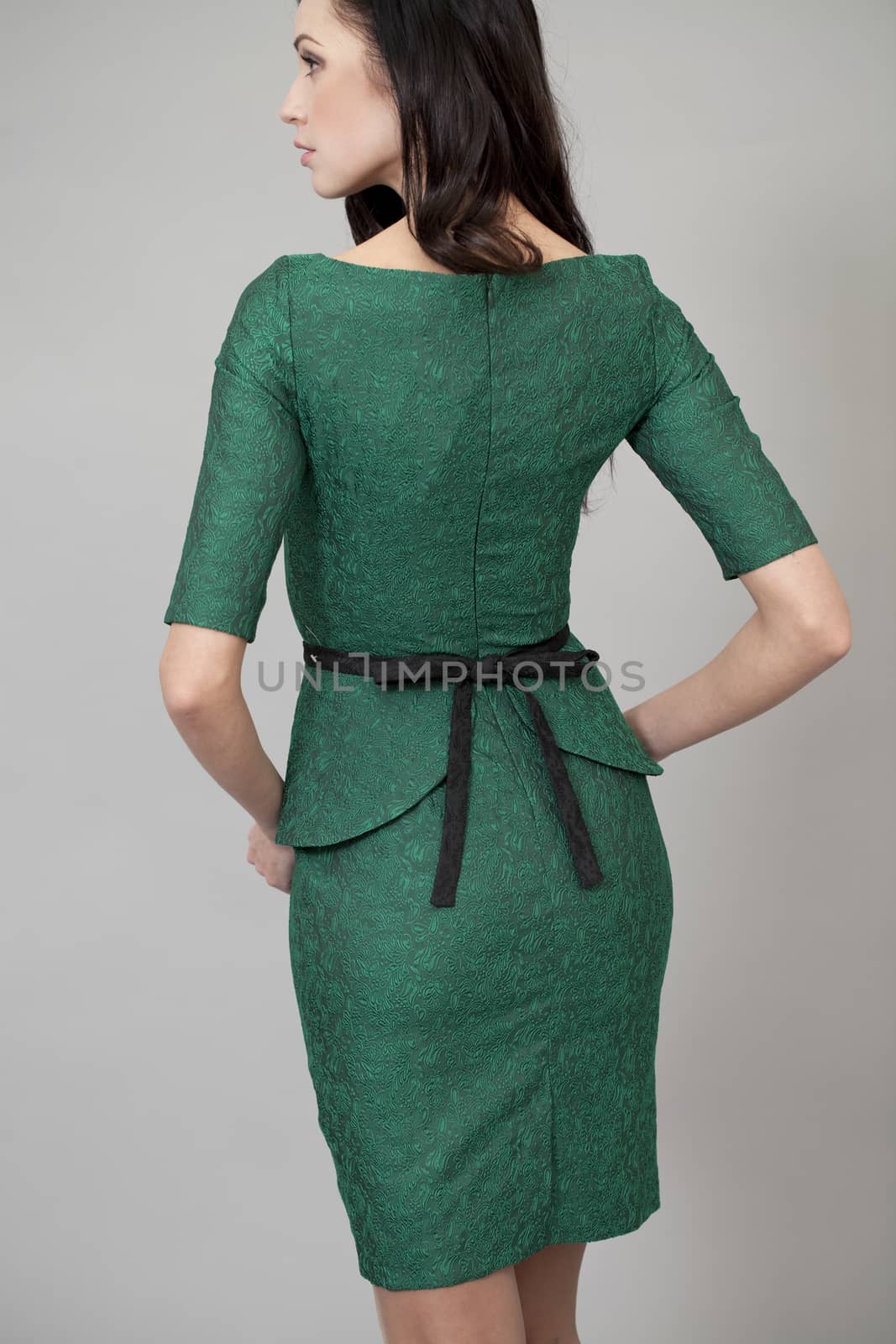 Young beautiful woman in green dress posing on grey background