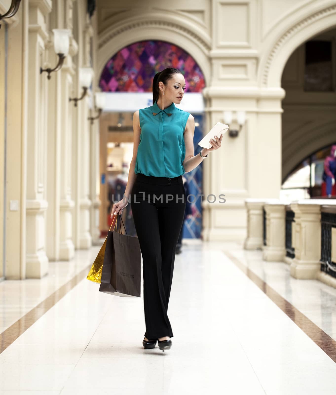 Happy young woman walking in the shop by andersonrise