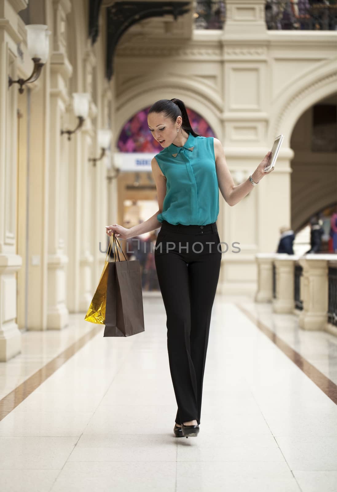 Happy young woman walking in the shop by andersonrise