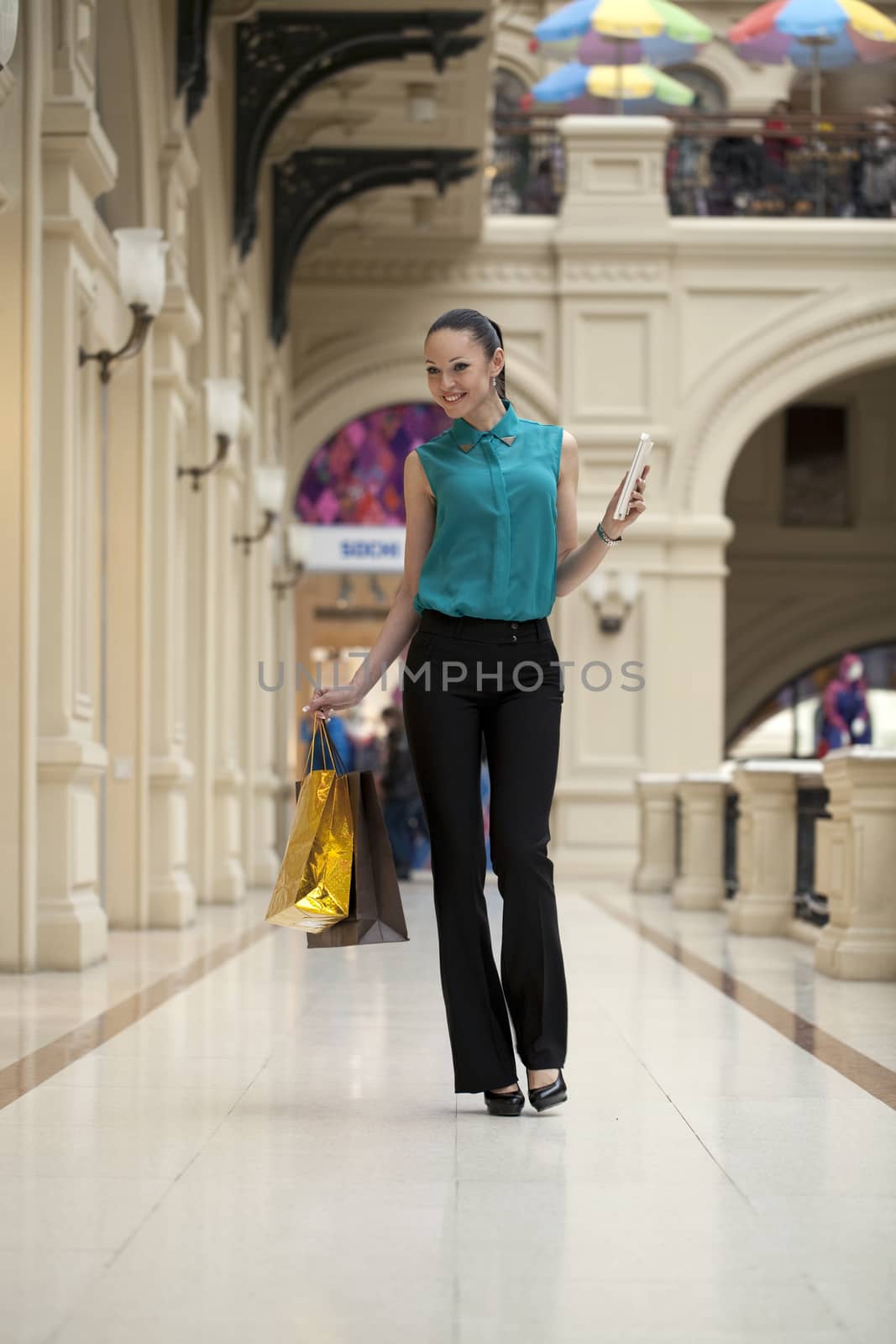 Happy young woman walking in the shop by andersonrise